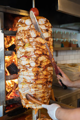 Chef cutting with doner knife Traditional Turkish Doner Kebab meat. Shawarma or gyros. Turkish, greek or middle eastern arab style chicken doner kebab food on isolated white.