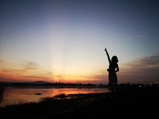Silhouette of free woman enjoying freedom feeling happy at sunset. Serene relaxing woman in happiness