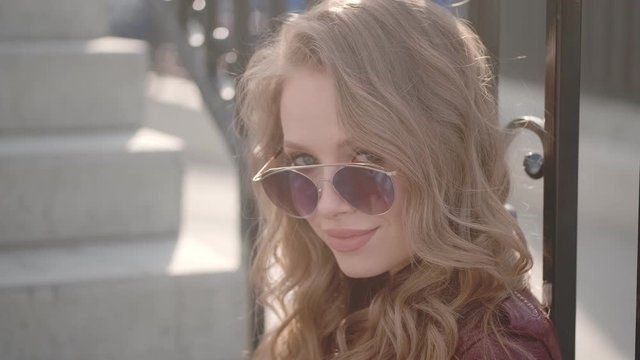 Attractive girl playfully looks at the camera over sunglasses