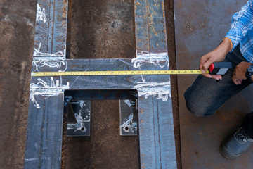 Technician use a measuring tape  to measure the dimension of steel structure work.