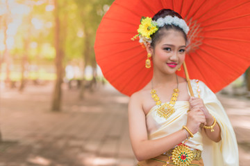 The beautiful traditional Thai dancer raises a red umbrella. It's the traditional Thai dance of the north of Thailand, southeast Asia.