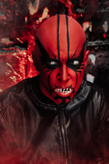 halloween make up. scary person ready for party. man with a false bald head and red demon makeup on...