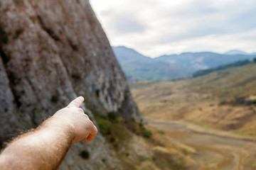 Person hand pointing at the horizon on the mountains