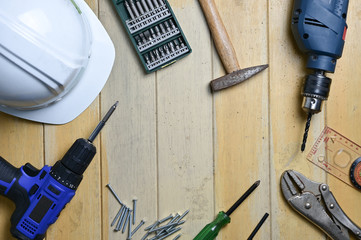 Carpentry tools of cordless drills,  screw driver, screws, hammer and accessories on wood table, top view design