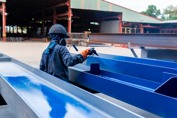 The painter is working to painting the steel structure with spray gun at industrial factory. focus...