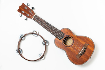 Ukulele and wooden tambourine. White background.