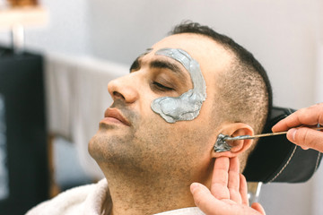 Male face waxing. Barber removes hair by shugaring from the face of turkish man.