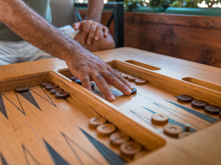 Male playing a traditional oriental board game of backgammon. Men's hands moving chips