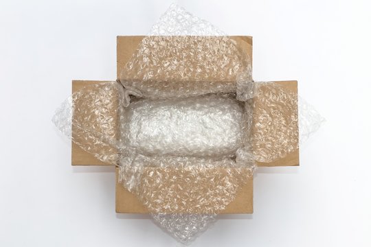 Plastic air bubble wrapped items in a brown parcel cardboard box, ready to be shipped.