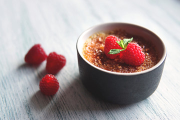 Creme brulee or catalana  with raspberries . Traditional French, Spanish and Italian vanilla cream dessert with caramelized brown sugar. Delicious,  tasty, sweet dish. Copy space. Selective focus