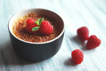  Creme brulee or catalana  with raspberries . Traditional French, Spanish and Italian vanilla cream dessert with caramelized brown sugar. Delicious,  tasty, sweet dish. Copy space. Selective focus