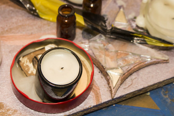 A white, extinguished candle in a dark glass, stands in a melted candle in a metal box