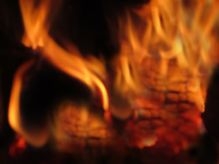 Blurred. Fire in the fireplace close-up. Forks of flame on charcoal background. Defocused.