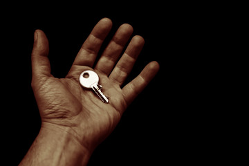 shiny key in the open hand palm on a black background copy space