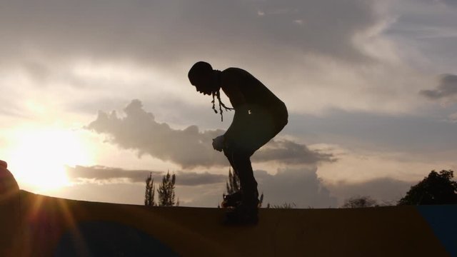 Silhouette of Young man jumping on the ramp using rollerblades 