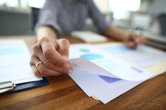 Male hands hold documents with financial statistics at office work-space closeup.