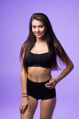 Fototapeta premium Sexy woman in black lingerie posing isolated on a violet background