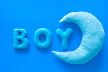 Baby shower concept. Word Boy and moon toy on blue background top view copy space