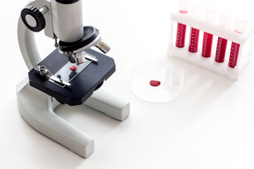 Blood testing laboratory. Samples viewing under microscope near tubes on white background top view copy space