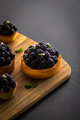 Blackberry and Hazelnut Cheesecakes in a Black Table. Dark moody Background