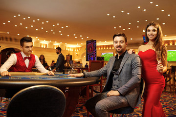 Young couple playing poker cards roulette in a casino.