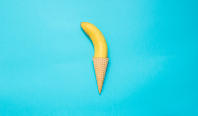 Yellow banana in a waffle cone on a blue background