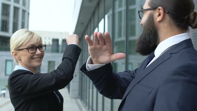 Smart blonde woman giving male colleague high-five gesture, business winners