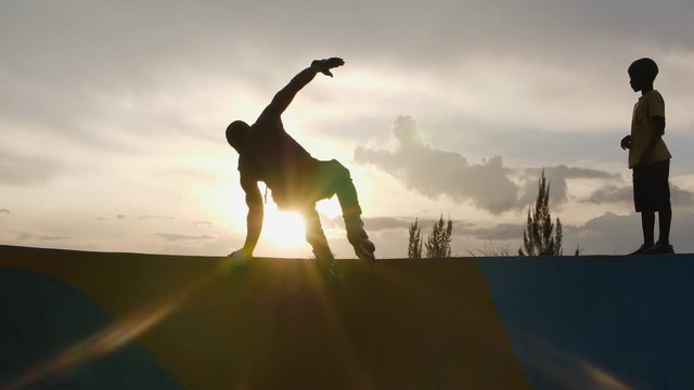 silhouette of a man jumping on the ramp in the skatepark with rollerblades