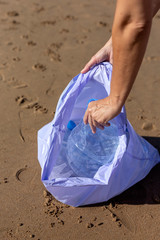 Woman picking up trash and plastics cleaning the beach