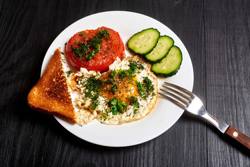 Grilled egg and grilled tomato on a plate on a wooden background. Fast and easy to prepare breakfast.