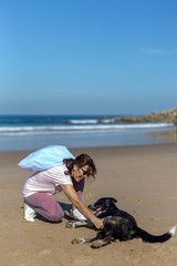 Woman with dog picking up trash and plastics cleaning the beach