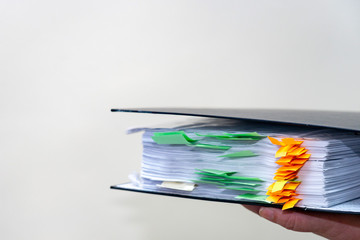 Give the folder with the financial report. Female hand holds a business paper file. A large bundle...