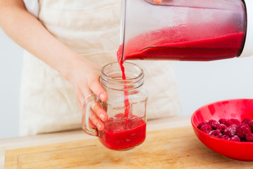 Berry Smoothie A woman pours a fruit smoothie from a shaker into a glass beaker. The concept of healthy eating.