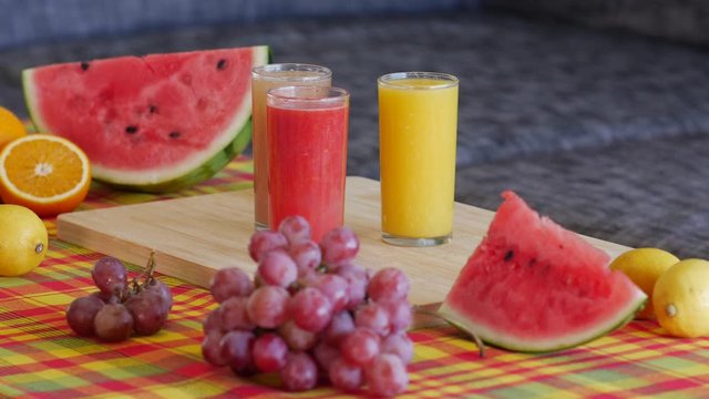 Table with Caribbean madras pattern tablecloth : Wooden plate containing fresh raw organic fruits and a glass of orange juice. beautiful morning Natural light.