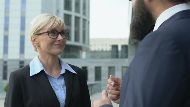 Smiling female office worker listening to boss outside building, private chat