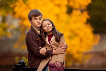 Fototapeta premium Loving boy and girl on a walk in the autumn park, sitting with their eyes closed and dreaming of something.