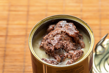 Open can of canned beef stand on the tourist table. Basic hike food ingredient.