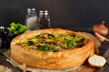 Quiche with mushrooms, onions and broccoli on a concrete background. Pie with mushrooms.