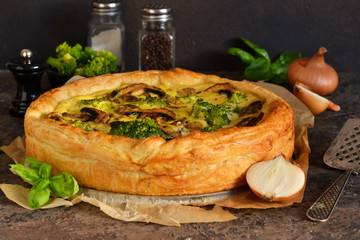 Quiche with mushrooms, onions and broccoli on a concrete background. Pie with mushrooms.
