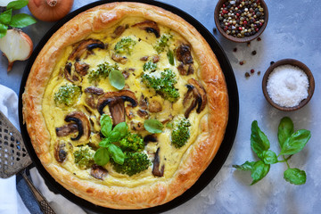 Quiche with mushrooms, onions and broccoli on a concrete background. Pie with mushrooms.