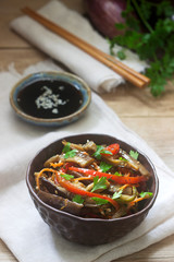 Oriental style vegetable salad with eggplant, soy sauce and chopsticks on a wooden table. Rustic style.