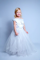 Fototapeta na wymiar little girl in a wedding dress. pretty little girl in beautiful white dress isolated on light background