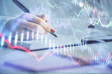 Multi exposure of woman's hands making notes with forex graph hologram. Concept stock market...