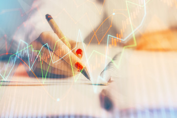 Double exposure of woman's hands making notes with forex graph hologram. Concept stock market analysis.