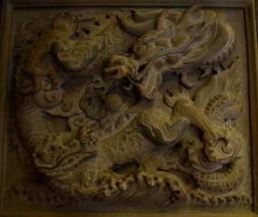 Traditional decoration of a stone carved dragon on the wall of a Chinese temple