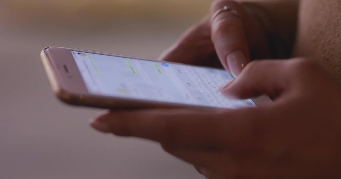 Closeup of woman hands texting writing messages on a smartphone in a night city communicating with her friend 