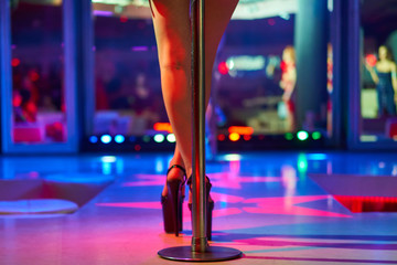 Heels of sexy woman pole dancing or striptease. Pylon in night club. Stripper girl background