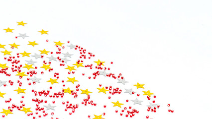 Christmas composition decoration. Pattern made of silver and gold star, golden decorations and red berries on white background.