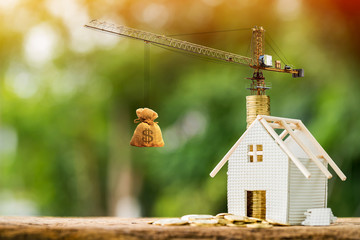Home with stack gold coin with growing interest value and tower crane with money bag in the public...
