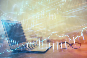Stock market graph on background with desk and personal computer. Double exposure. Concept of financial analysis.